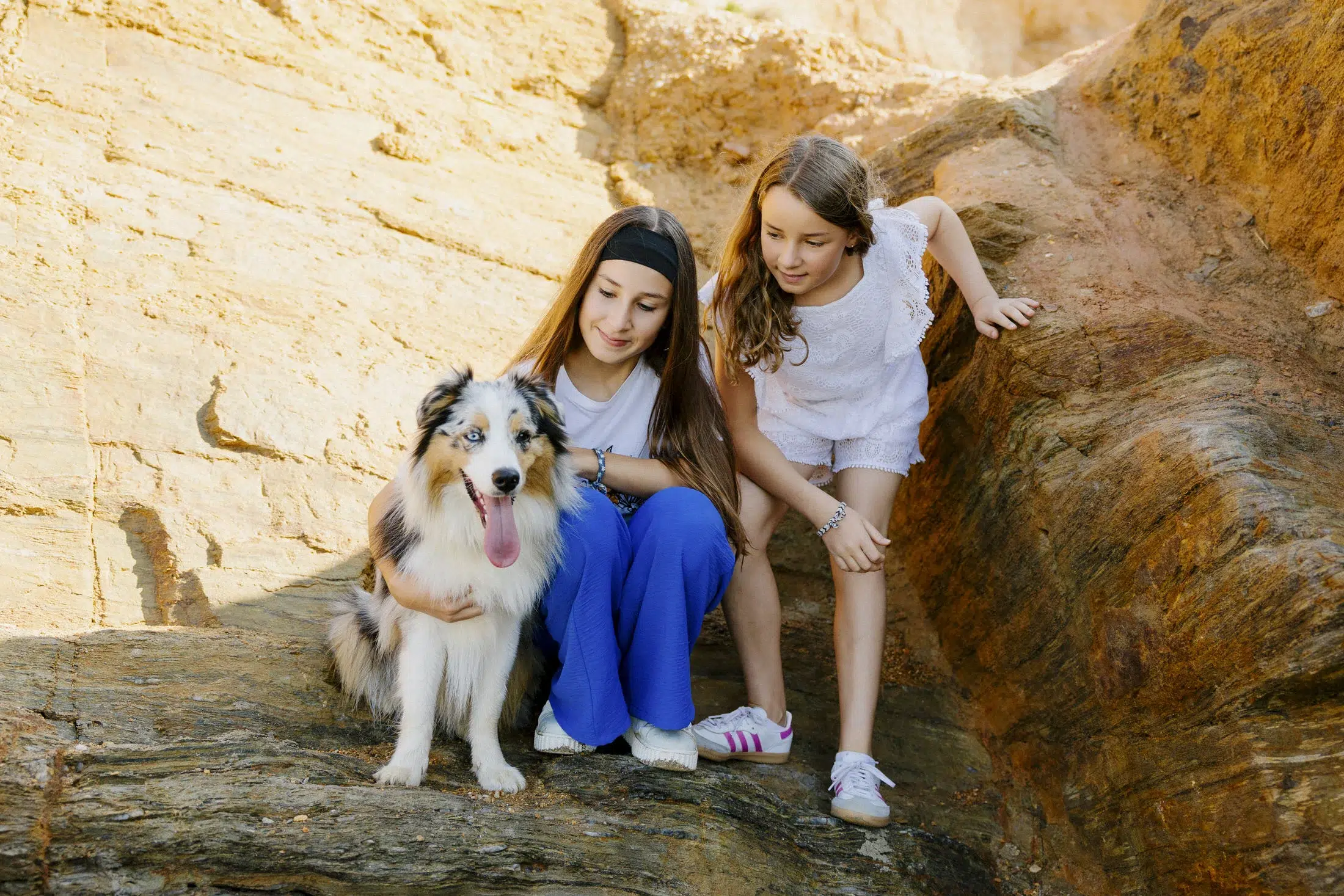 Deux sœurs câlinant leur chien sur les rochers à Pénestin.
