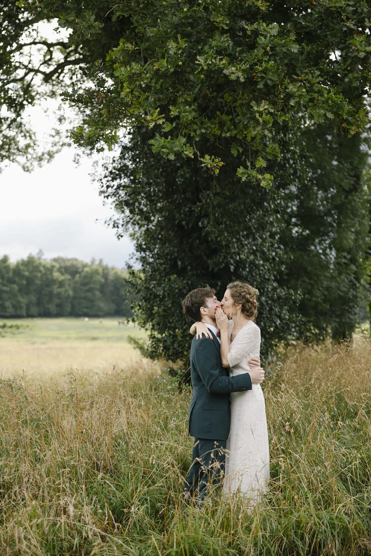 Photographe mariage Nantais, couple de jeunes mariés s’embrassant dans un champ au cœur de la nature