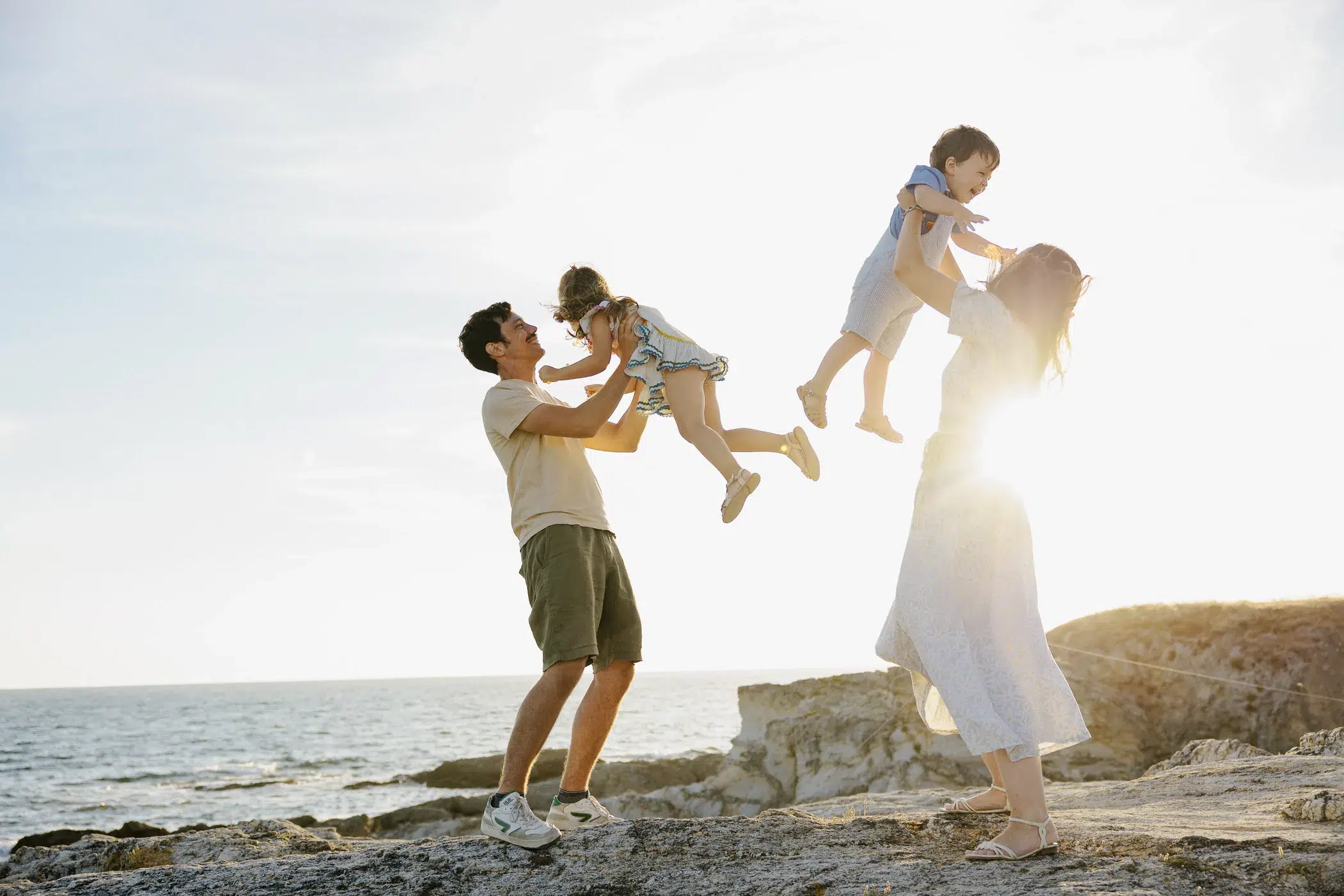 Séance photo famille au Pouliguen, parents faisant voler leurs enfants en l'air au bord de l'océan