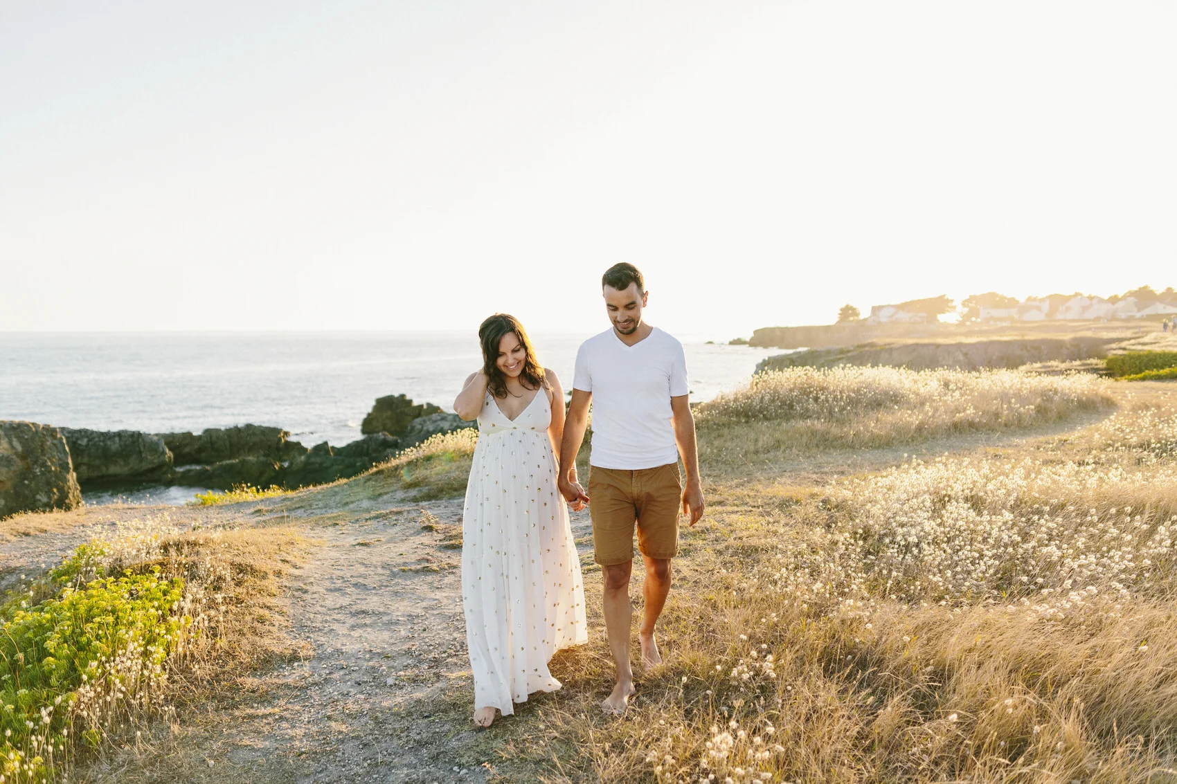 Séance photo grossesse au Pouliguen, couple marchant pieds nus sur la côte sauvage au coucher du soleil